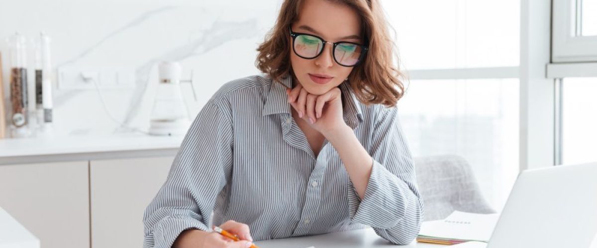 young-concentrated-businesswoman-glasses-striped-shirt-working-with-papers-home
